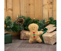 Ancol Georgia Gingerbread dog toy with a golden-brown body, white icing-style outlines and red and green buttons, pictured beside Christmas presents.