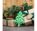 Ancol Squeaky Christmas Tree dog toy with a green festive pattern and short trunk, leaning against a wrapped Christmas present.