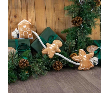 Ancol Gingerbread Rope dog toy with a brown gingerbread house, person and angel attached along a white rope, pictured among Christmas presents.