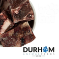 Frozen venison chunks in a bowl beside the Durham Animal Feeds logo.